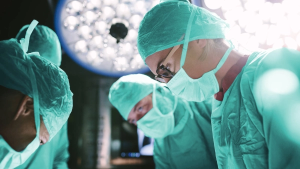 Four surgeons in scrubs performing an operation in the operating theatre
